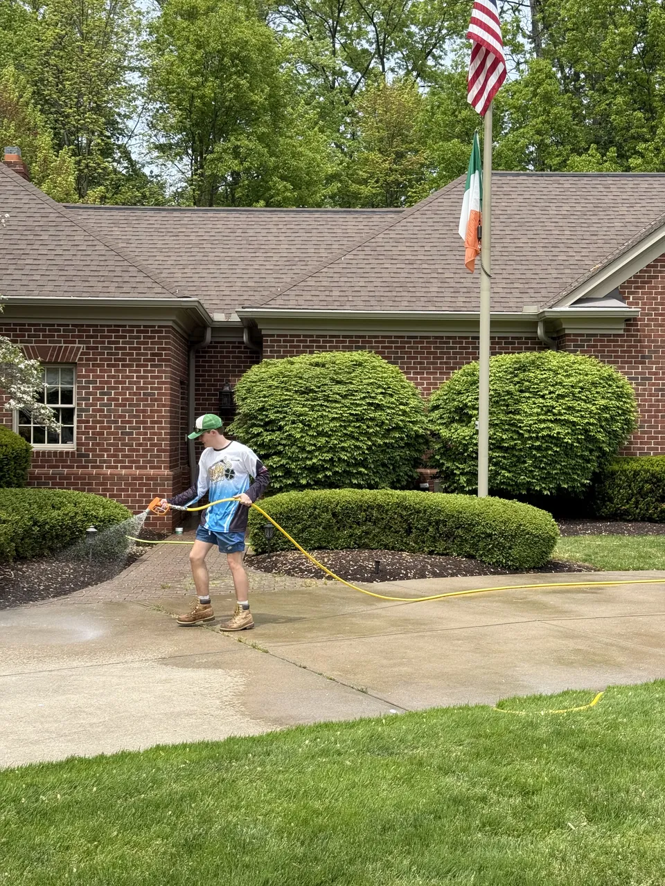 A Patty's Pressure Washing technician cleaning a concrete walk beside a brick ranch