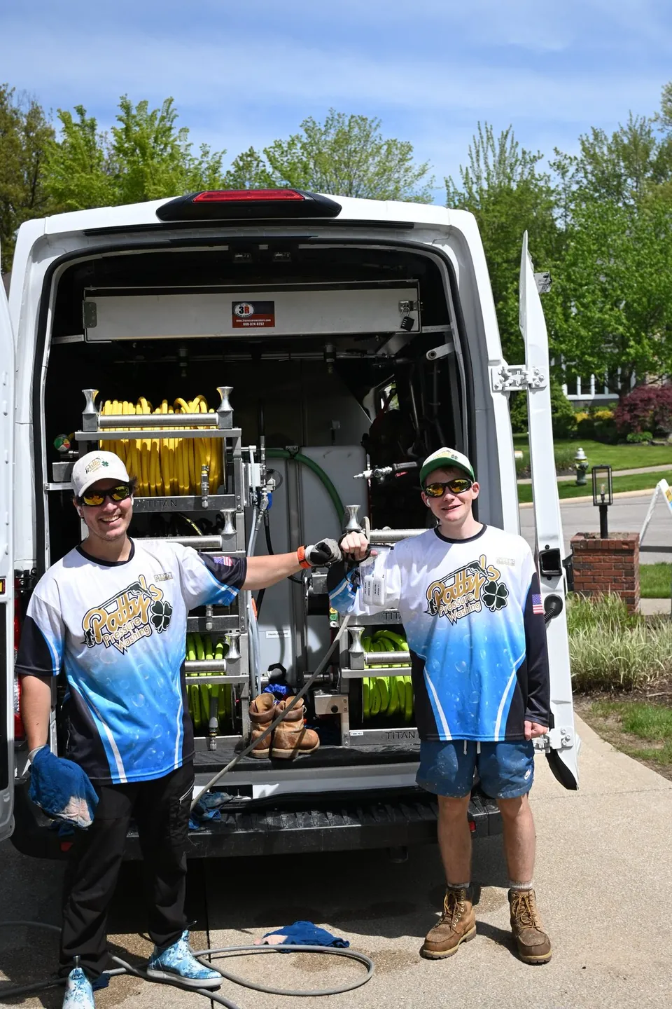 Two Patty's Pressure Washing technicians standing at the open rear doors of the company's service van
