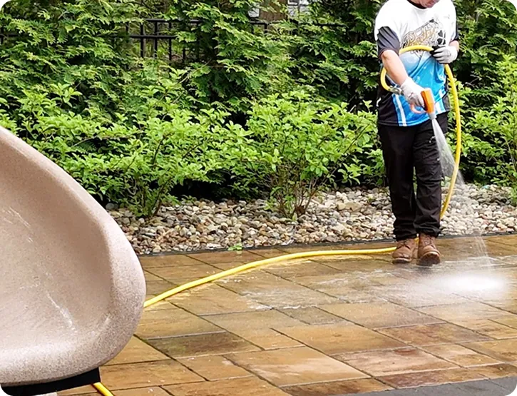 Technician pressure washing a paver patio with a surface cleaner