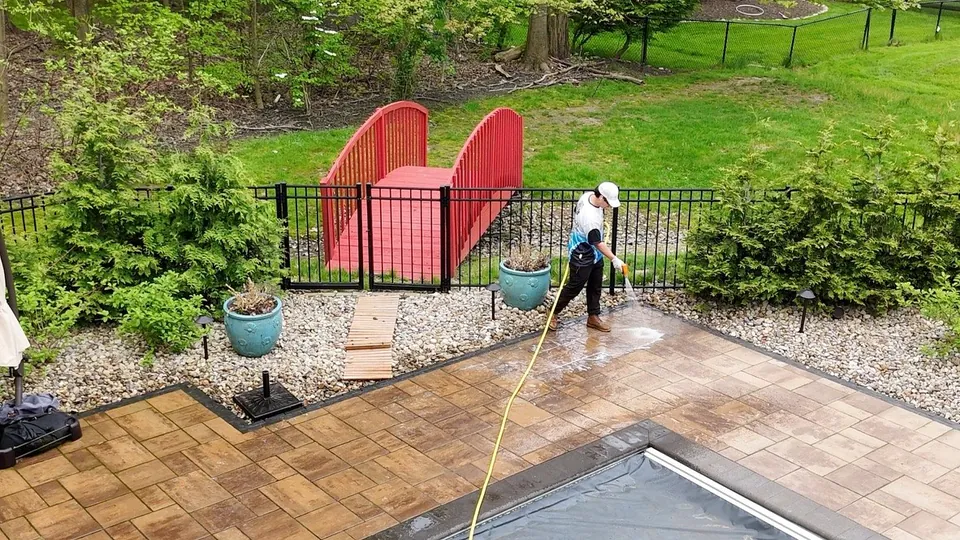 A Patty's Pressure Washing technician rinsing a paver pool deck in Orange, Ohio